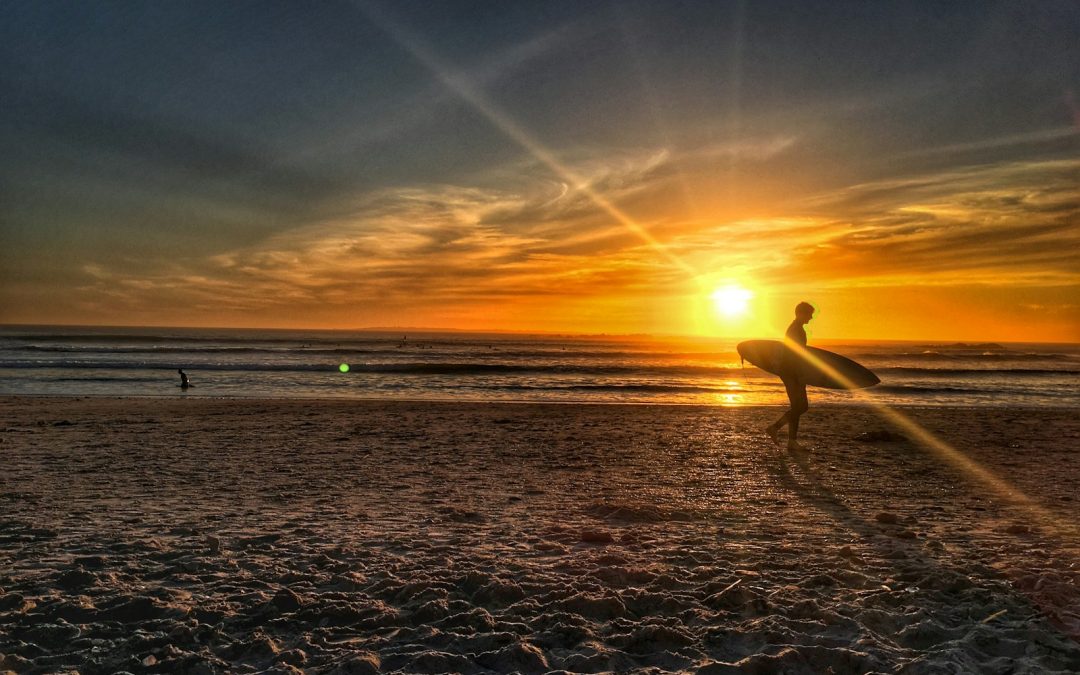 silhouette of person walking on shore during golden hour